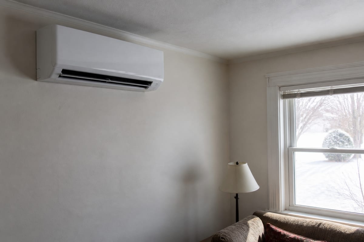 Wall-mounted ductless indoor head in a living room, snow on the ground outside