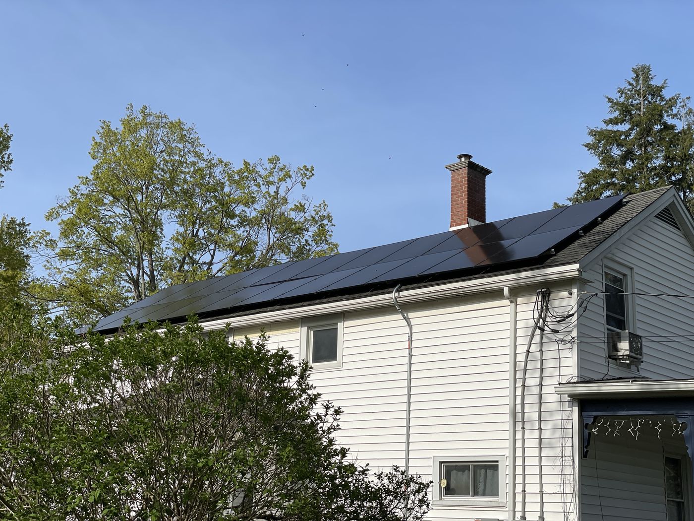 Roof-mounted black solar array on a white two-story clapboard home